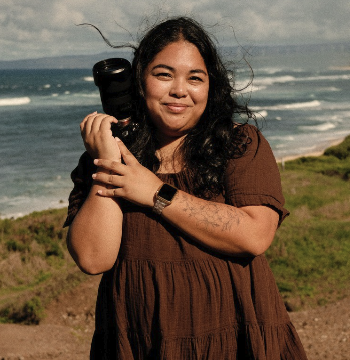 Edelyn holding a camera on a Hawaiian coastline