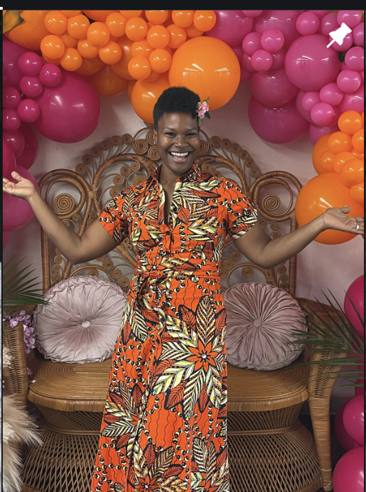 Liz Davis of Sparkle My Creations smiling in front of a pink and orange balloon backdrop
